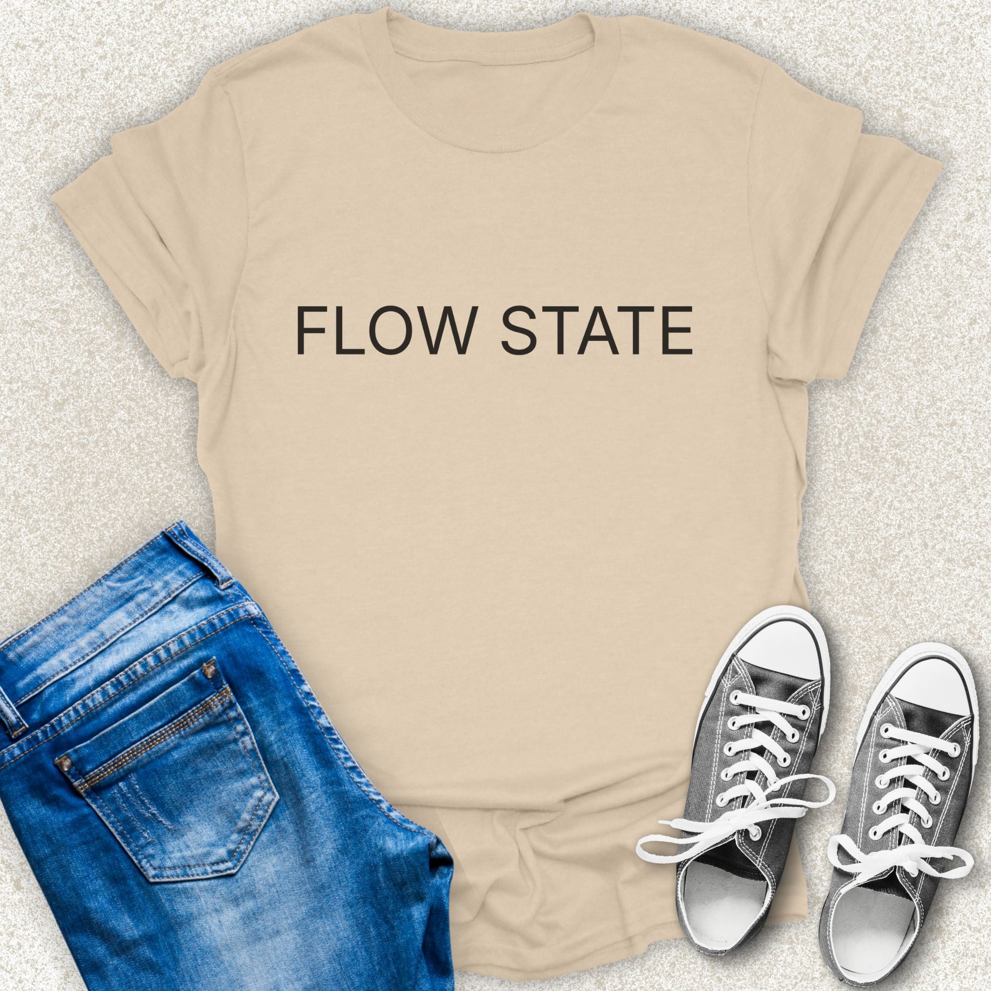 A Sand short-sleeve T-shirt with the words 'DEEP WORK' printed in white across the chest, styled in a flat lay with blue jeans and silver sneakers on a light textured background by Low Signal.