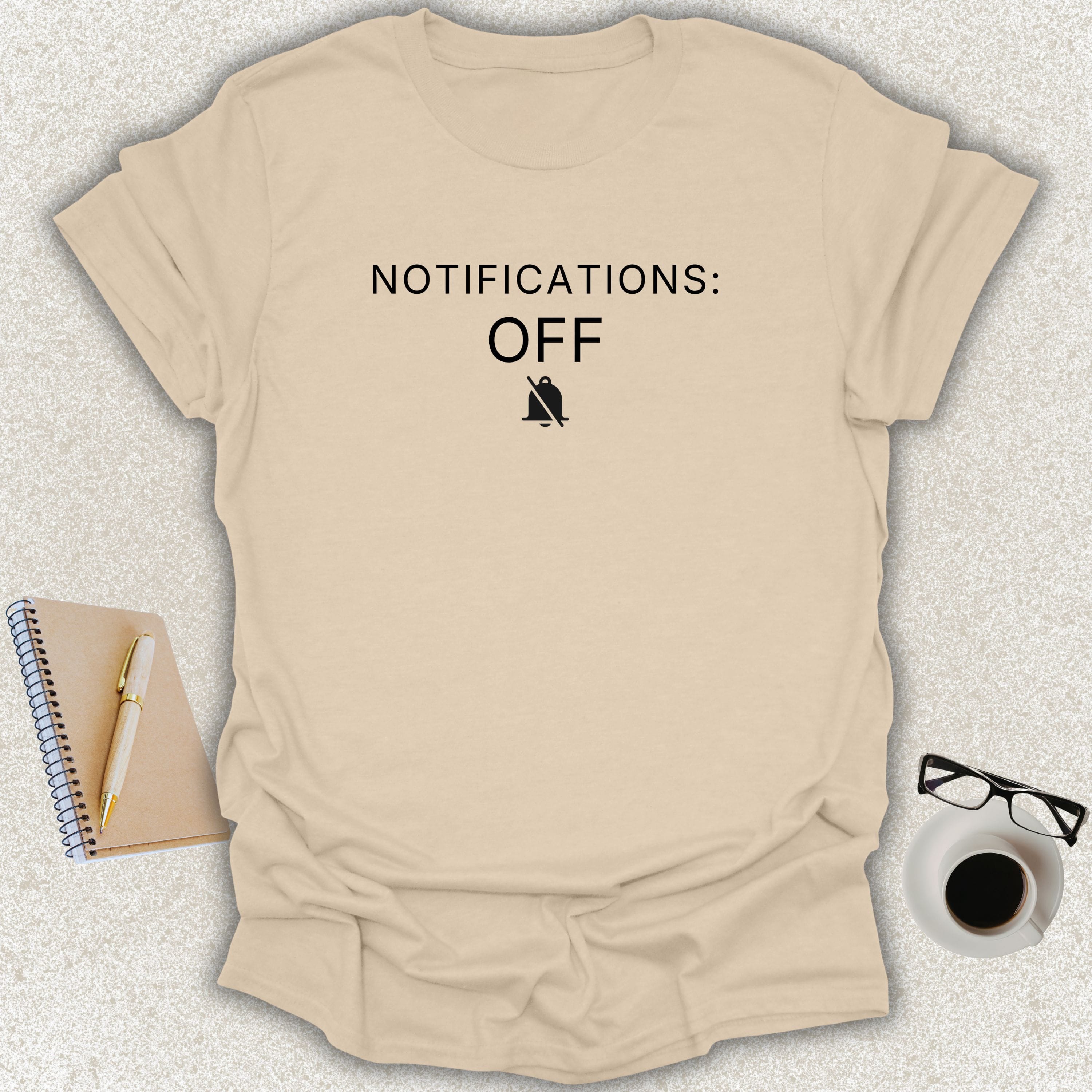 Low Signal NOTIFICATIONS: OFF minimalist typography t-shirt with muted notification bell icon on sand Gildan Softstyle tee
